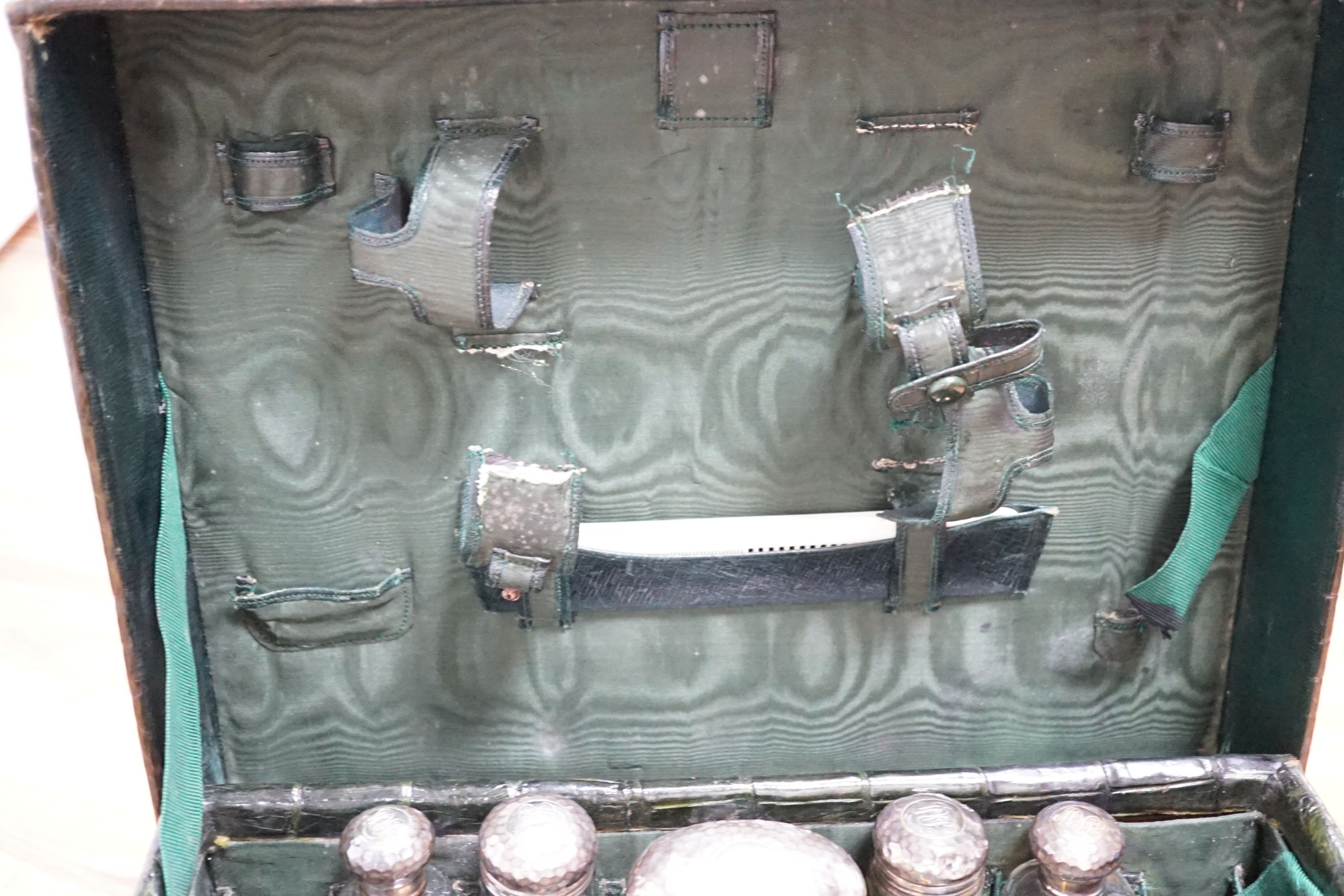 An early 20th century green crocodile toilet case with silver mounted interior, width 39 cms.